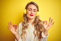 Young beautiful woman listening to music using headphones over yellow isolated background relax and smiling with eyes closed doing Royalty Free Stock Photo