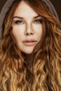 Young beautiful woman with long curly red hair in the hood. Close-up Royalty Free Stock Photo