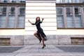 Young beautiful woman in a long dress walking along the road on the street in the background of a building Royalty Free Stock Photo