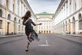 young beautiful woman in a long dress walking along the road on the street in the background of a building Royalty Free Stock Photo