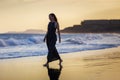 Young beautiful woman in long dress walking at la tejita beach at sunset Royalty Free Stock Photo