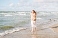 Young beautiful woman with long hair in beige sweater enjoying life on sea beach on sunset Royalty Free Stock Photo