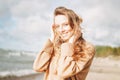 Young beautiful woman with long hair in beige sweater enjoying life on sea beach on sunset Royalty Free Stock Photo