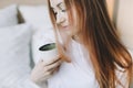 Young beautiful woman with cup of coffee or cacao in bed at home. Girl having breakfast in bed. Morning concept Royalty Free Stock Photo