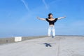 Young beautiful woman with long hair jumping on promenade against blue sky while looking camera with a big smile Royalty Free Stock Photo