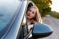 A young, beautiful woman with long hair sits at the wheel of the car and looks out the window Royalty Free Stock Photo