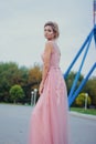 Young beautiful woman in long pink evening dress walking path in park. Fashion style portrait of gorgeous beautiful girl outdoors Royalty Free Stock Photo