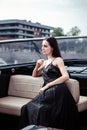 Young beautiful woman in a long silk black dress posing on a yacht. Luxurious life style