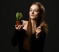 Young beautiful woman with long silky straight hair in black body holding cactus plant in pot and comparing with split ends Royalty Free Stock Photo