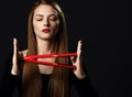 Young beautiful woman with long silky straight hair in black clothes with eyes closed holding red hair straightener Royalty Free Stock Photo