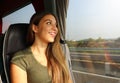 Young beautiful woman looking through the bus window. Happy bus passenger traveling sitting in a seat and looking through the