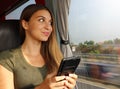 Young beautiful woman looking through the bus window. Happy bus passenger traveling sitting in a seat and looking through the