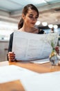 Young beautiful woman looking at menu deciding what to order in modern cafe. Royalty Free Stock Photo