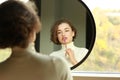 young woman looking in a mirror applying make up Royalty Free Stock Photo