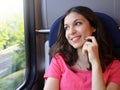 Young beautiful woman looking through the train window. Happy train passenger traveling sitting in a seat