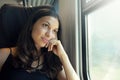 Young beautiful woman looking through the train window. Happy train passenger traveling sitting in a seat and looking through the Royalty Free Stock Photo