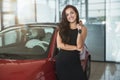 Young beautiful woman looks happy with car keys in her hand standing in dealership center buying brand new car Royalty Free Stock Photo