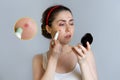 A young beautiful woman looks in the mirror and masks the rash on her face. An enlarged image of a pimple on the face. The concept Royalty Free Stock Photo