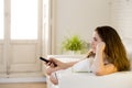 Young beautiful woman lying on couch holding remote control watching television happy and relaxed Royalty Free Stock Photo