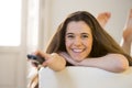 Young beautiful woman lying on couch holding remote control watching television happy and relaxed Royalty Free Stock Photo
