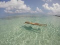 Young beautiful woman lying and floating on back in turquoise sea water on tropical paradise beach in Bora Bora Island, French