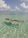 Young beautiful woman lying and floating on back in turquoise sea water on tropical paradise beach in Bora Bora Island, French