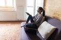 Young beautiful woman lying at her apartment living room on sofa couch holding remote control watching television. Happy and Royalty Free Stock Photo