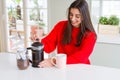 Young beautiful woman making morning coffee smiling, preparing a cup of latte for breakfast