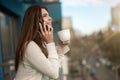 Young beautiful woman manager having phone conversation on the office balcony while drinking her coffee, looking happy, office Royalty Free Stock Photo