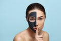 Young beautiful woman in a mask for the face of black clay . Girl mode Beauty face skin care . Spa treatment . Girl