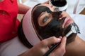 Young beautiful woman in a mask for the face of the therapeutic black mud in a beauty salon Royalty Free Stock Photo