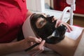 Young beautiful woman in a mask for the face of the therapeutic black mud in a beauty salon Royalty Free Stock Photo