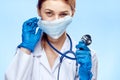 Young beautiful woman in medical clothes holds a stethoscope on a blue background Royalty Free Stock Photo