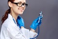 Young beautiful woman in medical clothes holds a syringe and stethoscope on a dark gray background Royalty Free Stock Photo