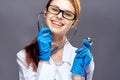 Young beautiful woman in medical clothes and wearing glasses on a dark gray background holds a stethoscope Royalty Free Stock Photo