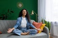 Young beautiful woman meditating in lotus pose, Hispanic woman smiling contentedly dreaming about future plans, sitting Royalty Free Stock Photo