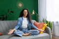 Young beautiful woman meditating in lotus pose, Hispanic woman smiling contentedly and looking at camera, sitting on Royalty Free Stock Photo