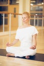 Young beautiful woman meditating in lotus pose sitting on the fl Royalty Free Stock Photo