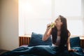 Young beautiful woman in morning bed at home. Eating and biting sandwich with green vegetables and tasty bread Royalty Free Stock Photo