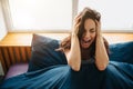 Young beautiful woman in morning bed at home. Sit and hold hands on head. Scream because of pain and stress. Depression Royalty Free Stock Photo