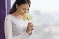 Young beautiful woman with natural makeup, long and healthy brown hair, girl with large pale yellow flower near the window, copy s Royalty Free Stock Photo