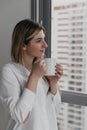 Young beautiful woman near window with cup of coffee or tea at home. Royalty Free Stock Photo