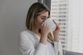 Young beautiful woman near window drinking cup of coffee or tea at home. Royalty Free Stock Photo