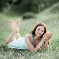 Young beautiful woman with orange lying on grass