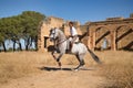 Young beautiful woman performing turns riding her horse in the countryside next to an abandoned and ruined building on a sunny day Royalty Free Stock Photo