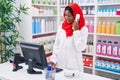 Young beautiful woman pharmacist talking on telephone using computer at pharmacy Royalty Free Stock Photo