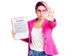 Young beautiful woman with pink hair holding clipboard with contract document doing stop sing with palm of the hand Royalty Free Stock Photo