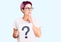 Young beautiful woman with pink hair holding question mark serious face thinking about question with hand on chin, thoughtful Royalty Free Stock Photo