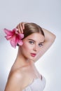 Young beautiful woman with pink lily flower on grey background. Skin care concept Royalty Free Stock Photo