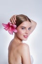 Young beautiful woman with pink lily flower on grey background. Skin care concept Royalty Free Stock Photo